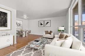 A living room with a white couch, a coffee table, and a dining table with chairs.