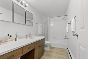 A white bathroom with a toilet, sink, and mirror.