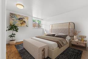 A bedroom with a large bed and a potted plant.