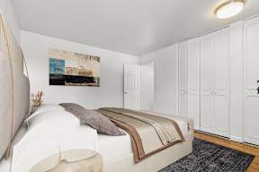 A bedroom with a bed, a painting on the wall, and a rug on the floor.