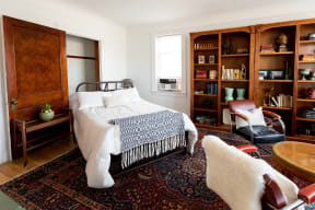 a bedroom with a bed and bookshelves     and a chair