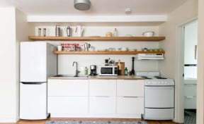 a white kitchen with a white refrigerator and a sink