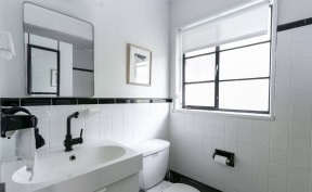 a white bathroom with a sink toilet and a window