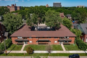 an aerial view of a red brick building with trees and a city in the background