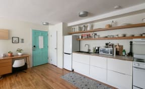 a small kitchen with white cabinets and a green door