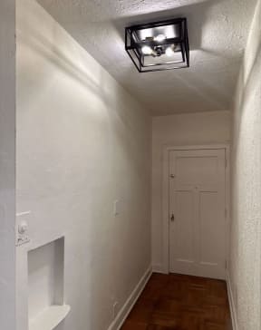 a small hallway with a white door and a ceiling light