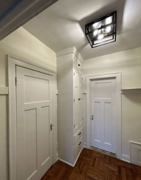 a hallway with white closets and a ceiling light