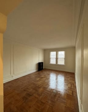an empty living room with a wooden floor and a window