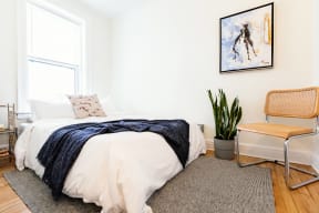 a bedroom with a bed and a plant and a window