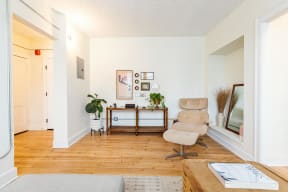 a living room with a wooden floor and a chair and a table