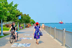 people walking and riding bikes on a path near the water