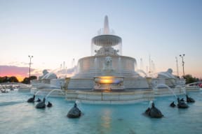 a fountain with ducks in the water at sunset