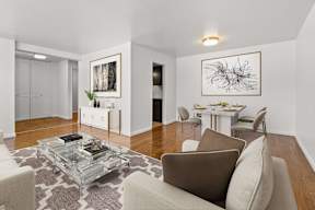 A living room with a glass coffee table and a brown couch.