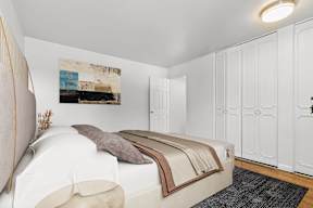 A bedroom with a bed, a painting on the wall, and a rug on the floor.