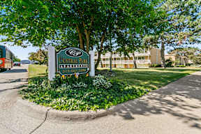 A sign for Central Park Apartments is surrounded by greenery.