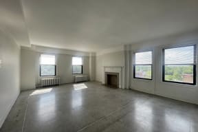 an empty living room with a fireplace and windows