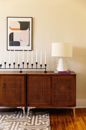 a sideboard with white candles and a painting on the wall