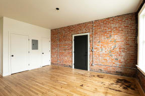 an empty room with a brick wall and wooden floors
