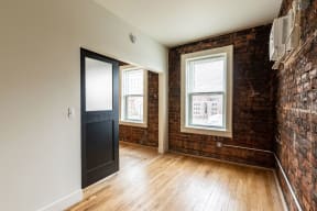 an empty room with a brick wall and wood floors and a black door