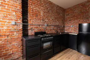a kitchen with black appliances and a brick wall