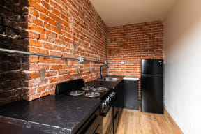 a kitchen with a stove and a brick wall