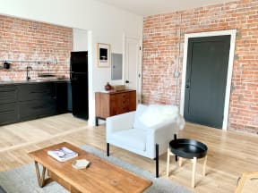 a living room with a white chair and a brick wall