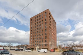 a tall brick building with cars parked in a parking lot