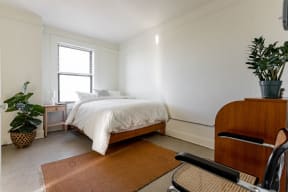 a bedroom with a bed and a dresser and a potted plant