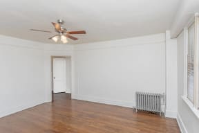 an empty living room with a ceiling fan and a radiator