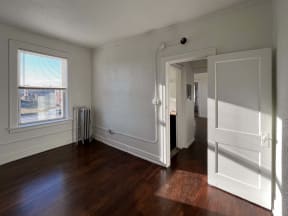 an empty living room with wood floors and a door to a hallway