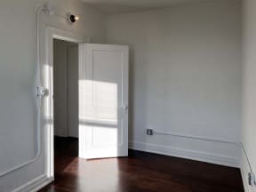 an empty room with a white door and wood floors