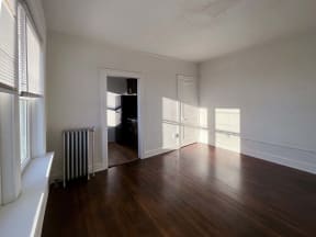 an empty living room with wood floors and a radiator