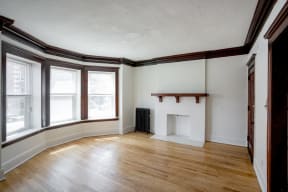 an empty living room with a fireplace and wood floors