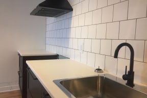 an empty kitchen with a sink and white tiled walls