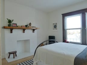a bedroom with a bed and a fireplace and a window