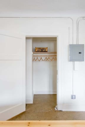a small closet with a white door and a shelf in it