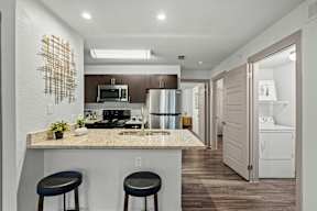 A kitchen with a granite countertop and a bar stool.