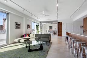 A modern living room with a glass table and grey couch.