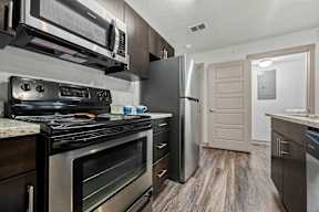 A modern kitchen with a stainless steel refrigerator and oven.