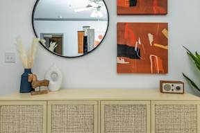 a room with a dresser and a mirror and paintings on the wall