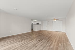 an empty living room with a ceiling fan and a kitchen