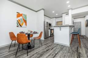 a dining area with a table and chairs and a kitchen with a refrigerator