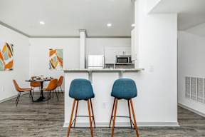 a kitchen and dining area with chairs and a counter with a microwave