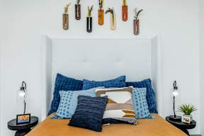 a bedroom with a bed with blue pillows and a white headboard and hooks