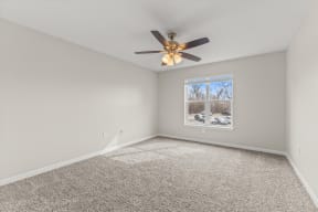 an empty living room with a ceiling fan and a window