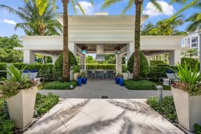 a patio with palm trees and a table and chairs under a building