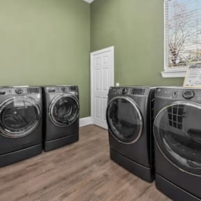 Three front load washing machines in a laundry room.