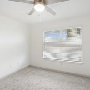 A room with a ceiling fan and a window with blinds.