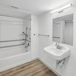 A white sink is mounted on a wall next to a glass shower stall.