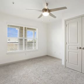 A room with a ceiling fan and a door.